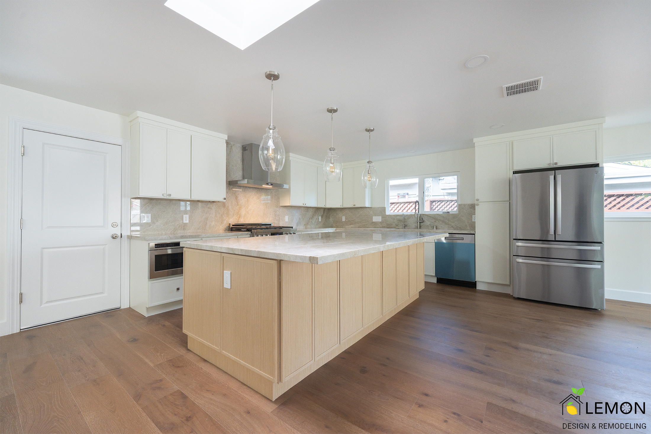 Modern open concept kitchen remodel featuring bi-color cabinetry, quartz countertops, oversized island, skylight, custom pantry storage, stainless steel appliances, and warm hardwood flooring designed to create a bright, functional, and timeless living space.